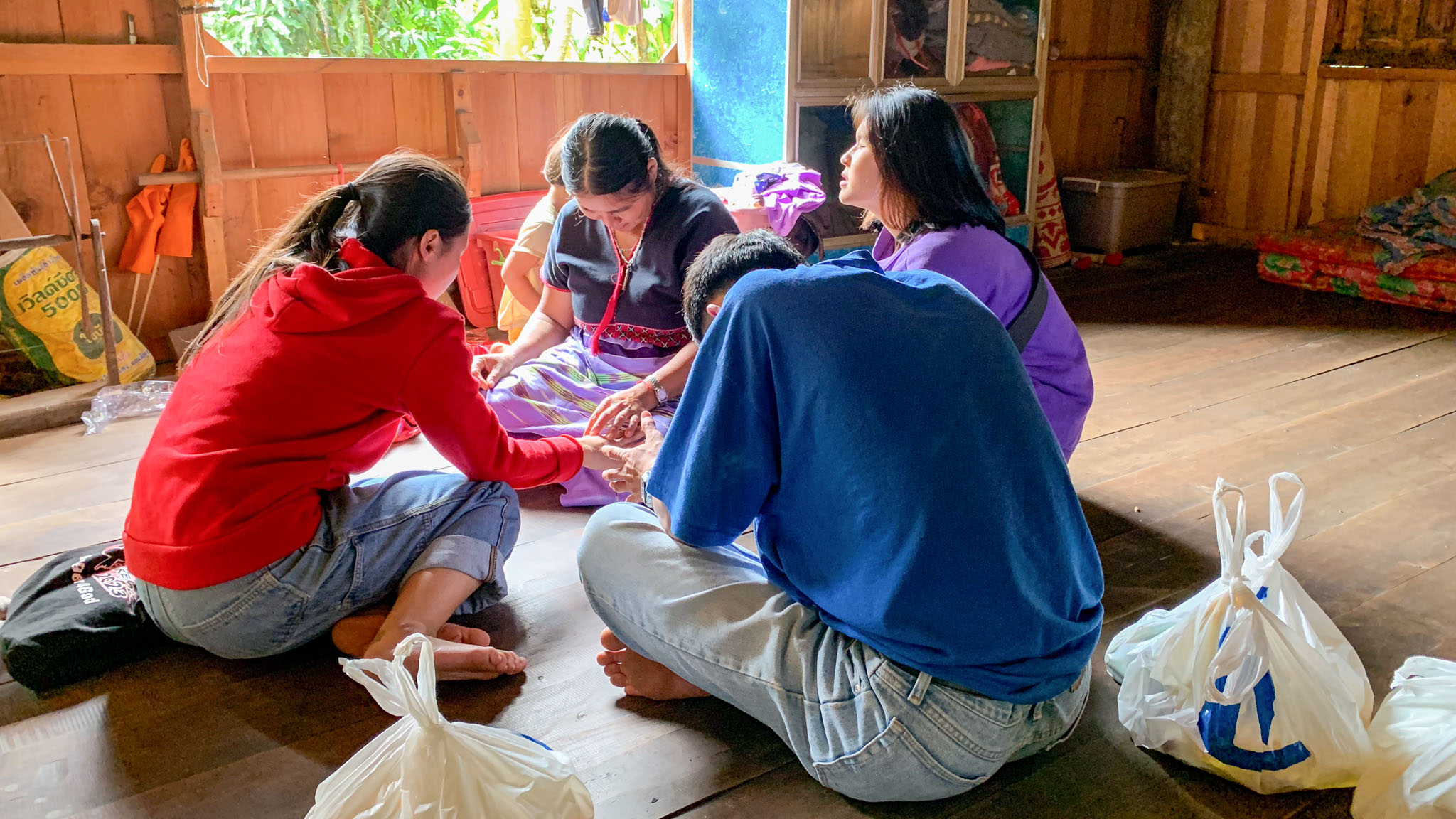 Four people sitting in a circle praying together